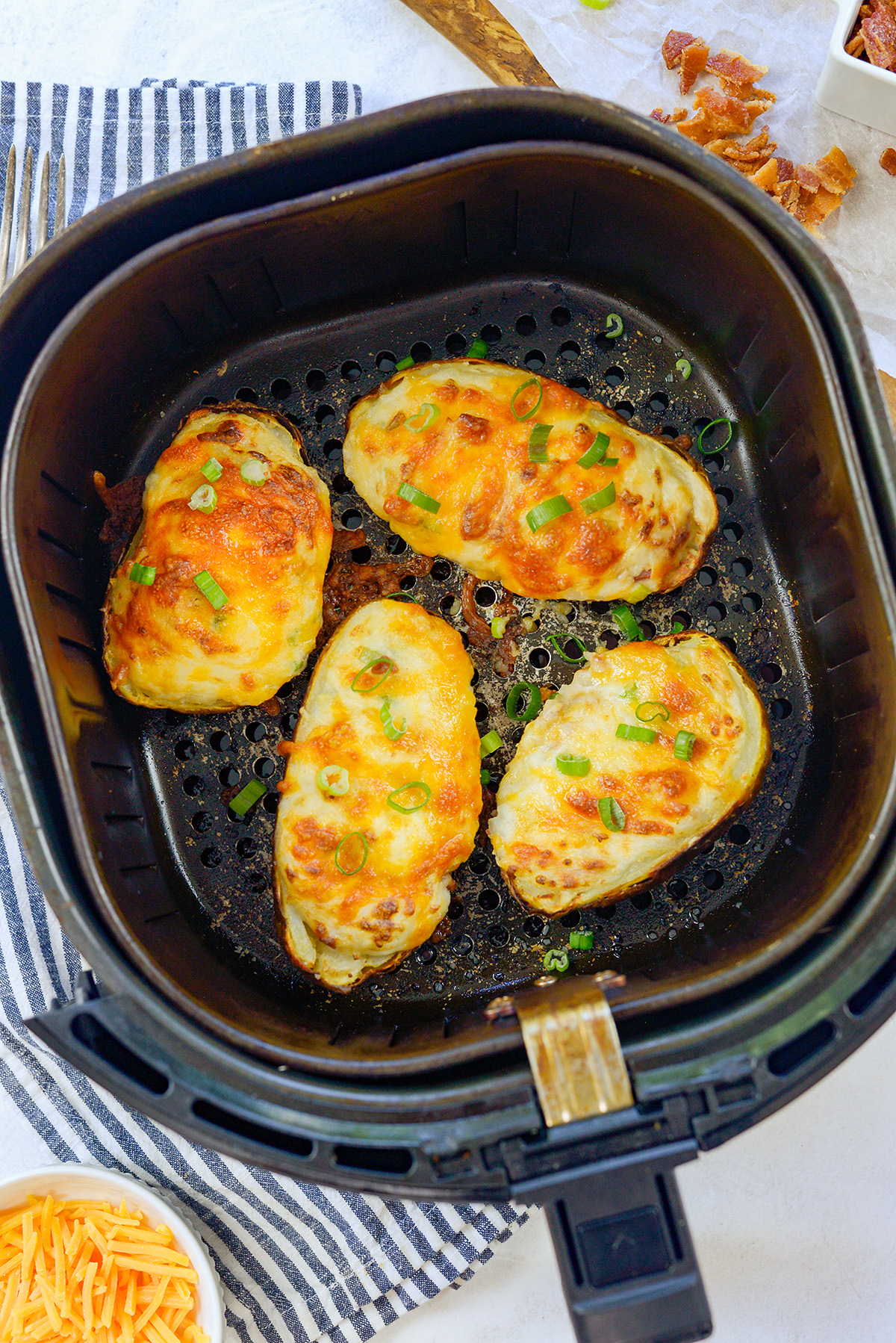Four twice baked potatoes in an air fryer basket.