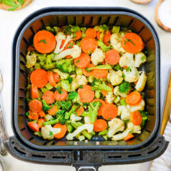 Overhead view of cooked veggies in an air fryer basket.