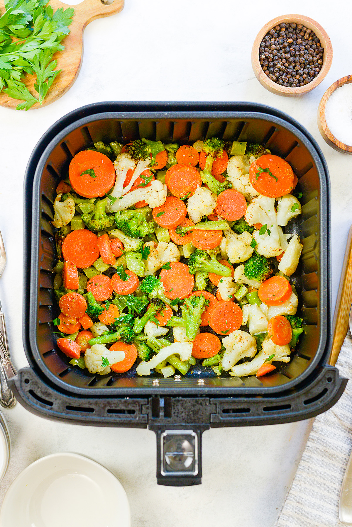 Overhead view of cooked veggies in an air fryer basket.