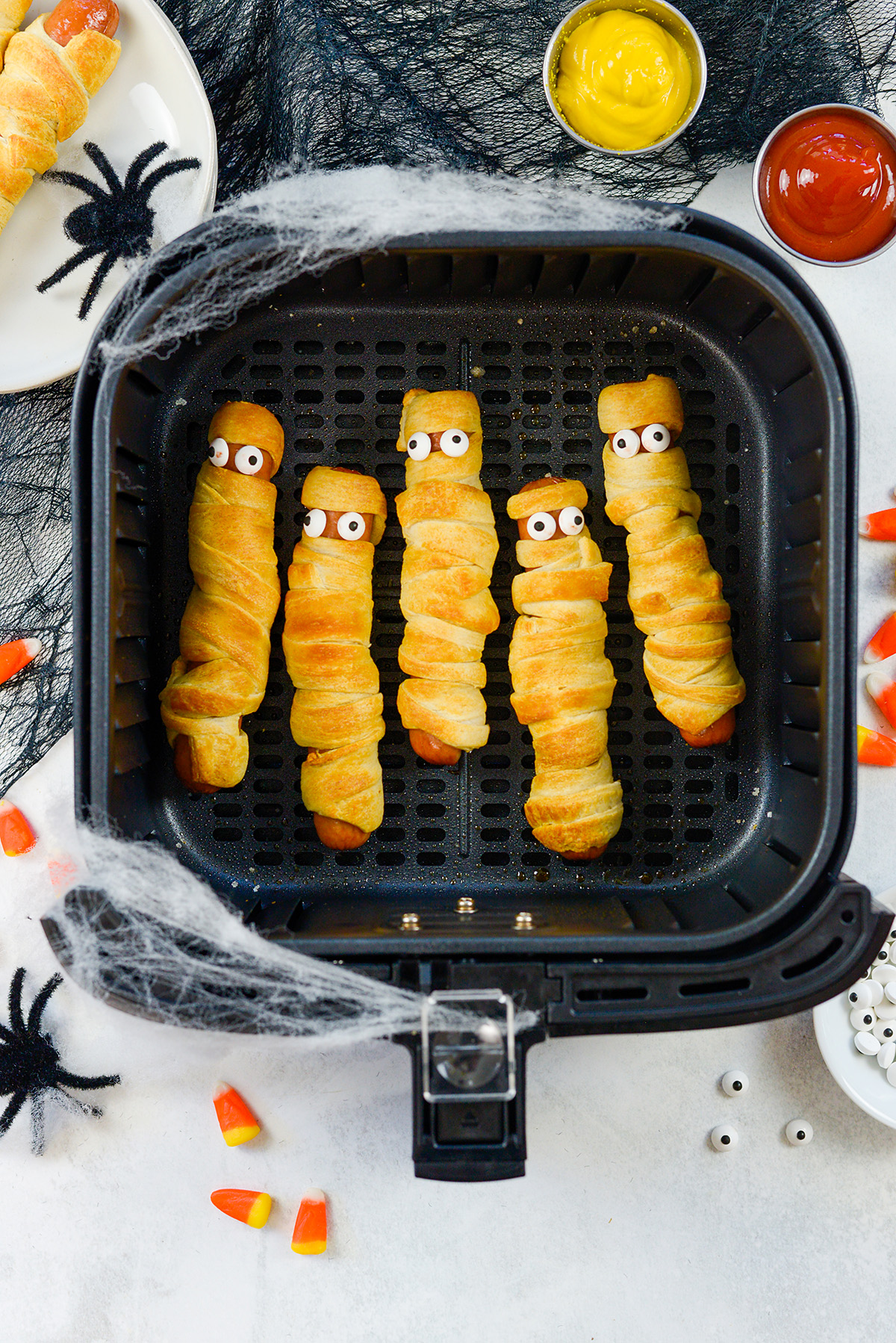 Overhead view of mummy dogs in an air fryer basket.
