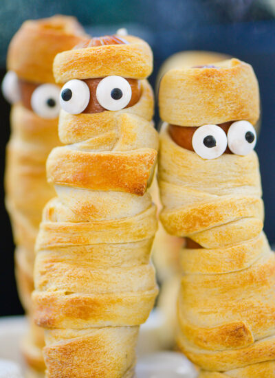 Two mummy hot dogs standing next to each other.