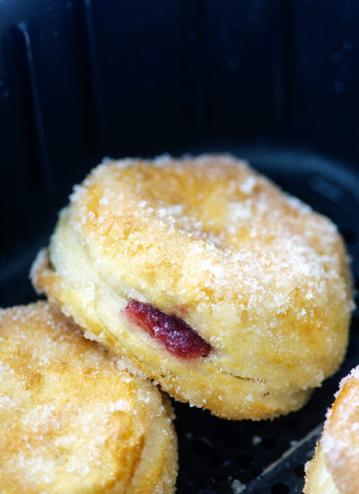 Close up of a sugar coated jelly donut in an air frryer basket.