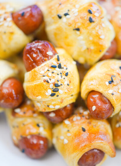 Close up of a pile of cooked and seasoned mini pigs in a blanket.