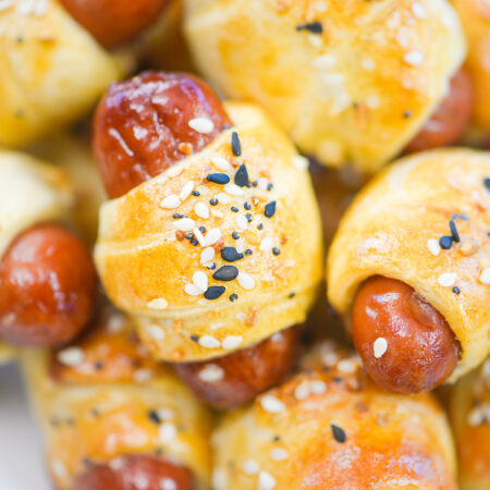 Close up of a pile of cooked and seasoned mini pigs in a blanket.