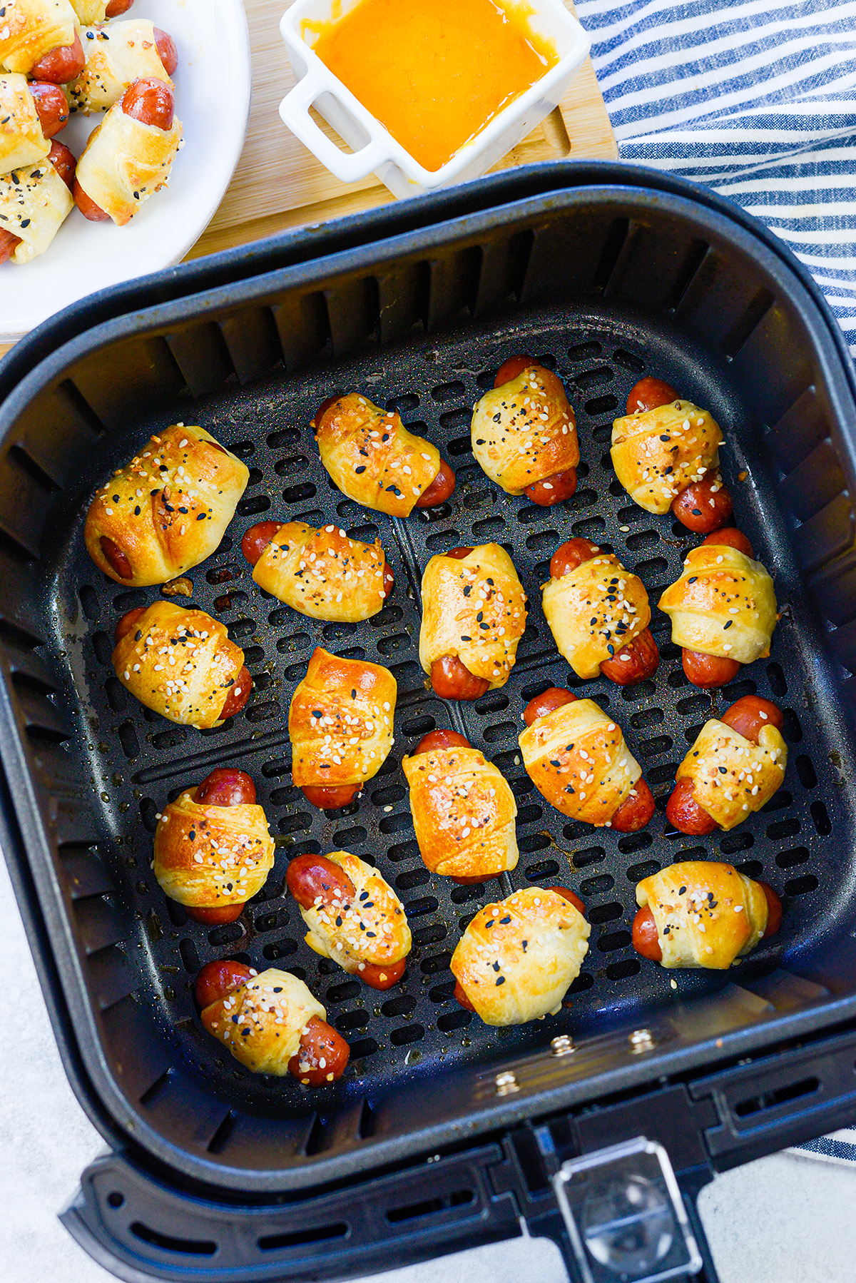 Cooked mini pigs in a blanket in an air fryer basket.