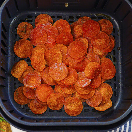 An air fryer basket full of pepperoni chips.