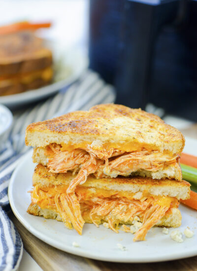 Two buffalo chicken grilled cheese sandwiches on a small white plate.