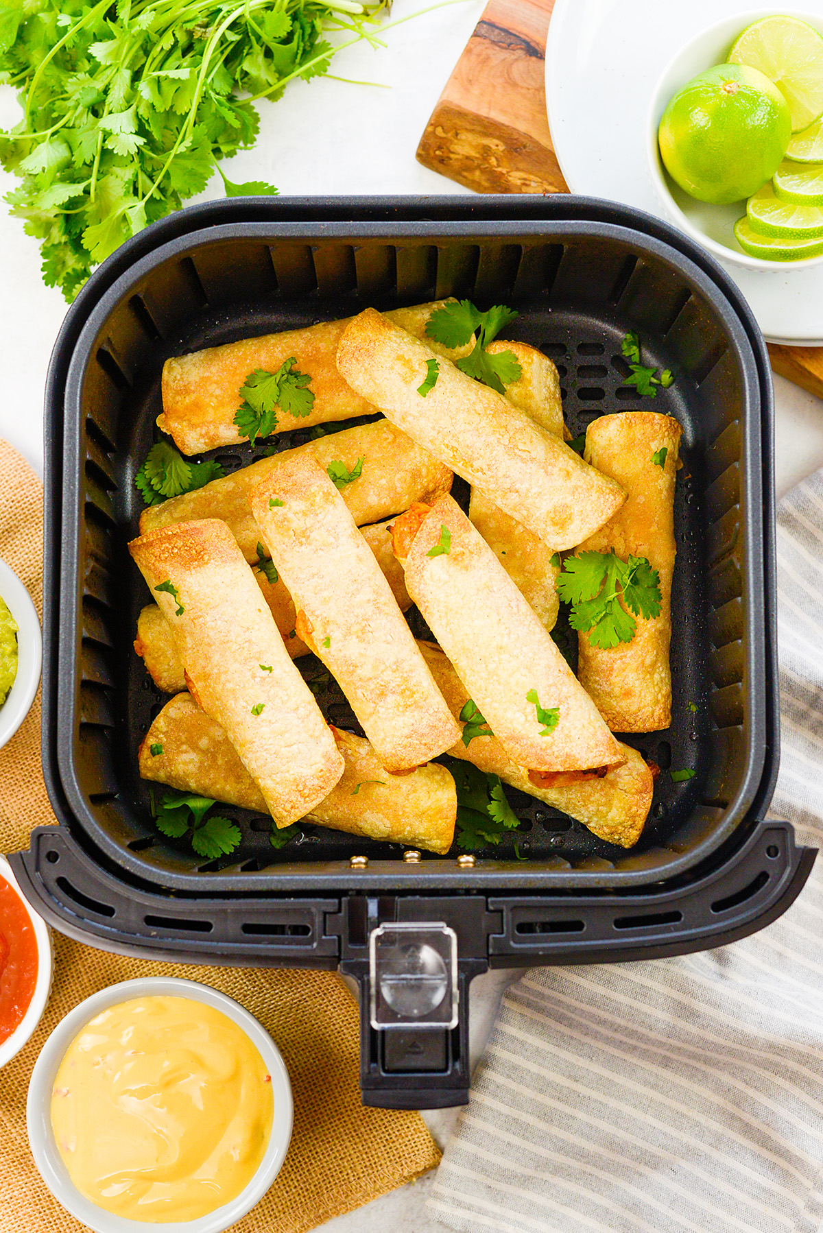 Cooked chicken taquitos stacked up inside of an air fryer basket.