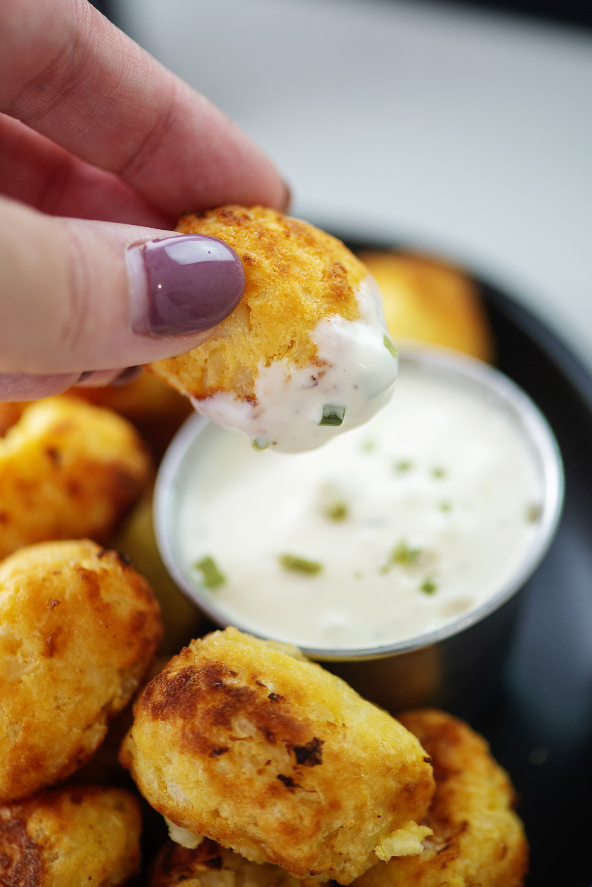 A person dipping cauliflower tots into ranch dressing.