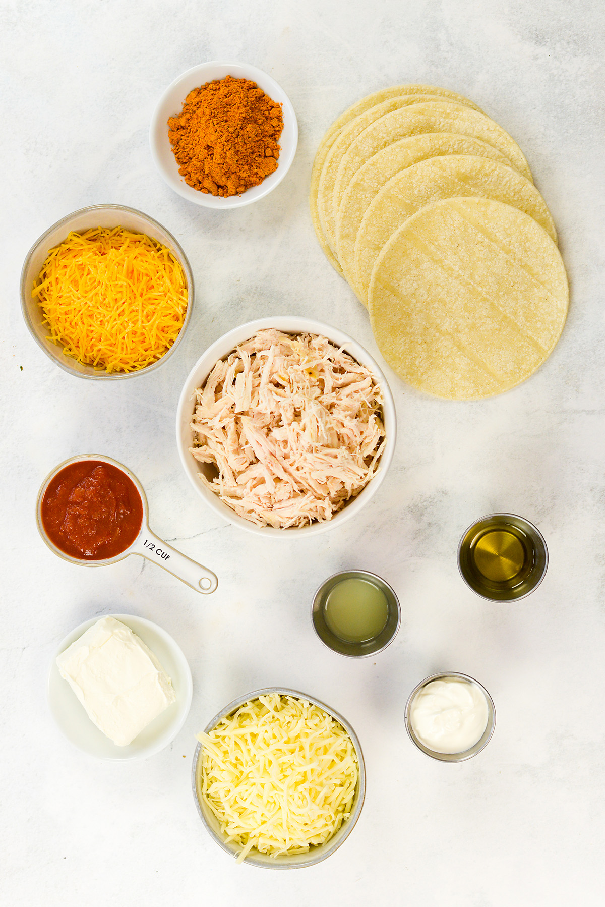 Ingredients for chicken taquitos spread on a white countertop.