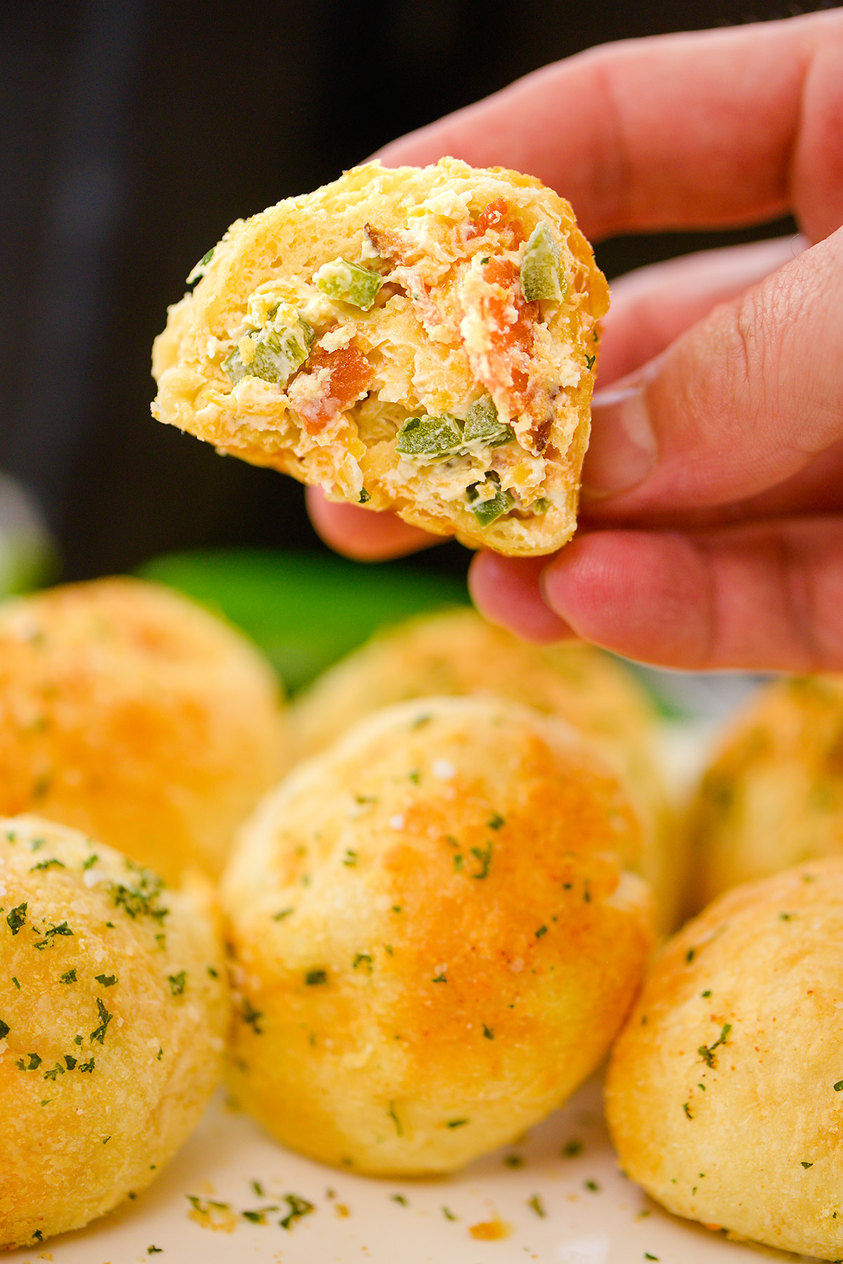 Close up of a jalapeno popper biscuit bite being held by a person.