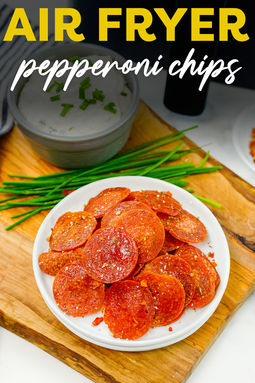Pepperoni chips on a small white plate in front of an air fryer.