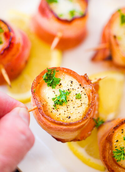 A person holding up a bacon wrapped scallop.