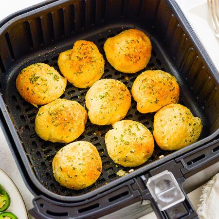 Three rows of jalapeno popper biscuit bombs in an air fryer basket.