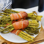 Bacon wrapped asparagus on a white plate.