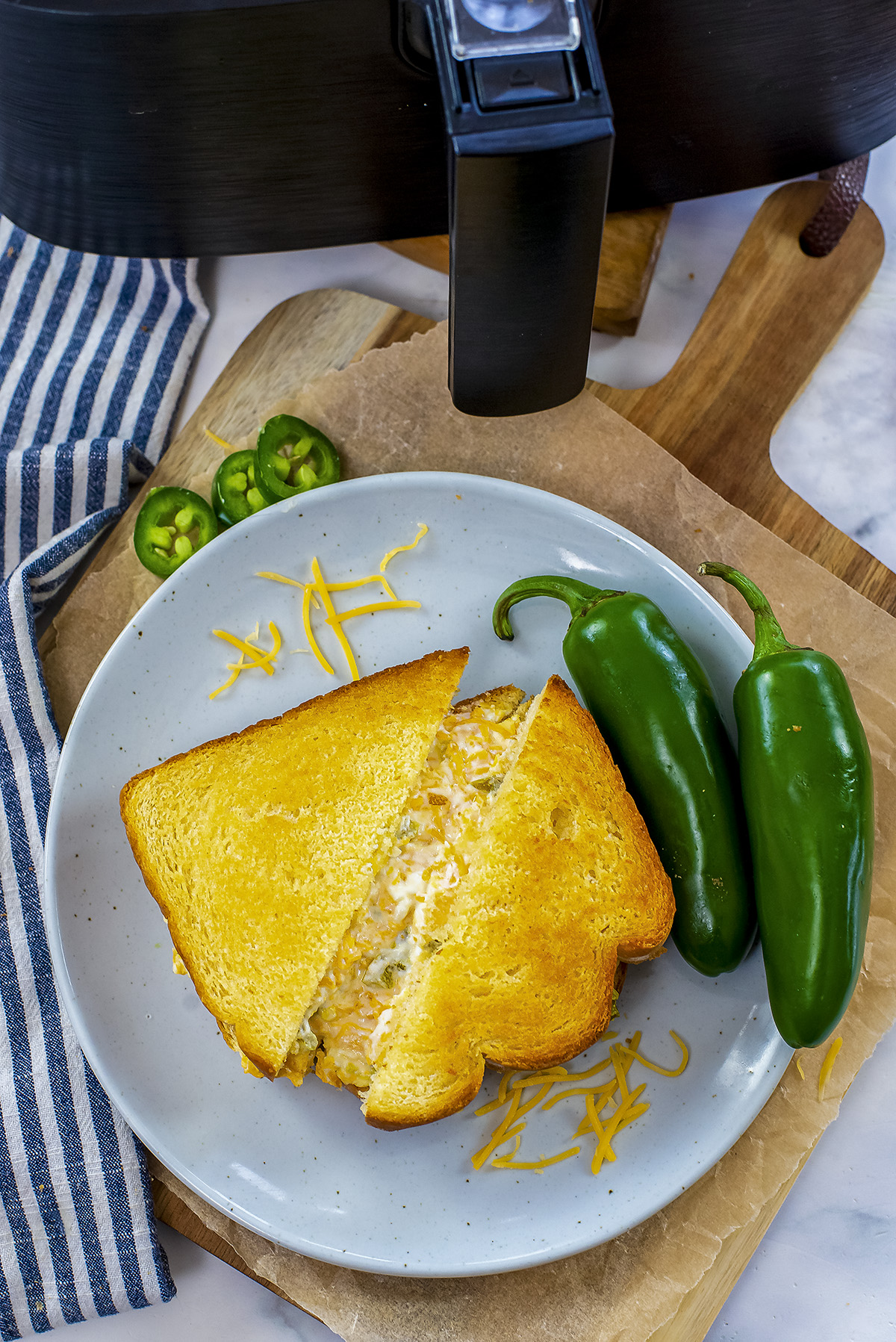 Jalapeno popper grilled cheese in front of an air fryer basket.