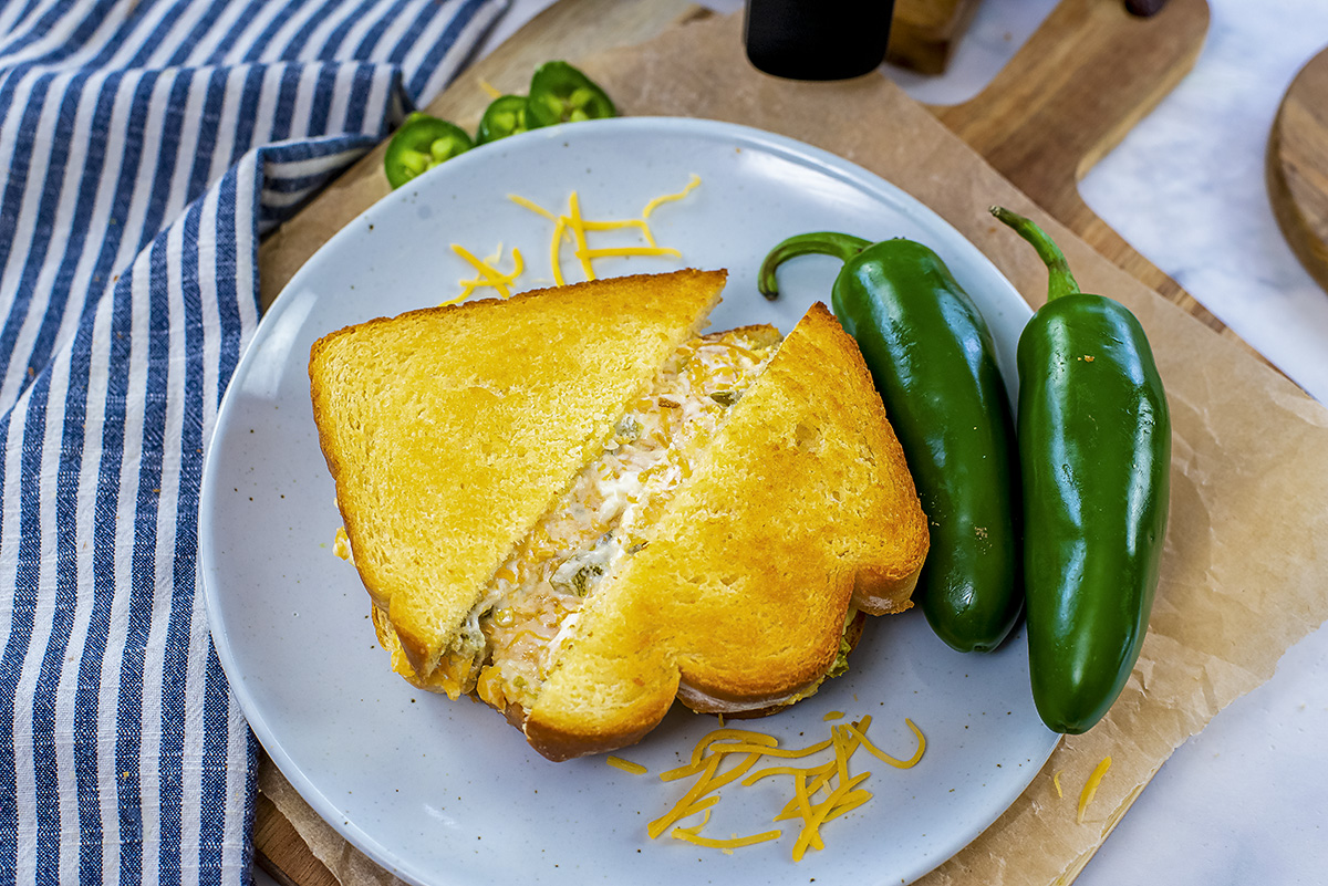 Jalapeno popper grilled cheese on a white plate.
