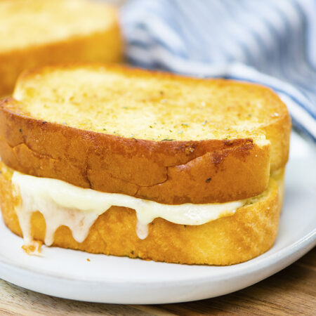 Garlic bread grilled cheese on a small white plate.