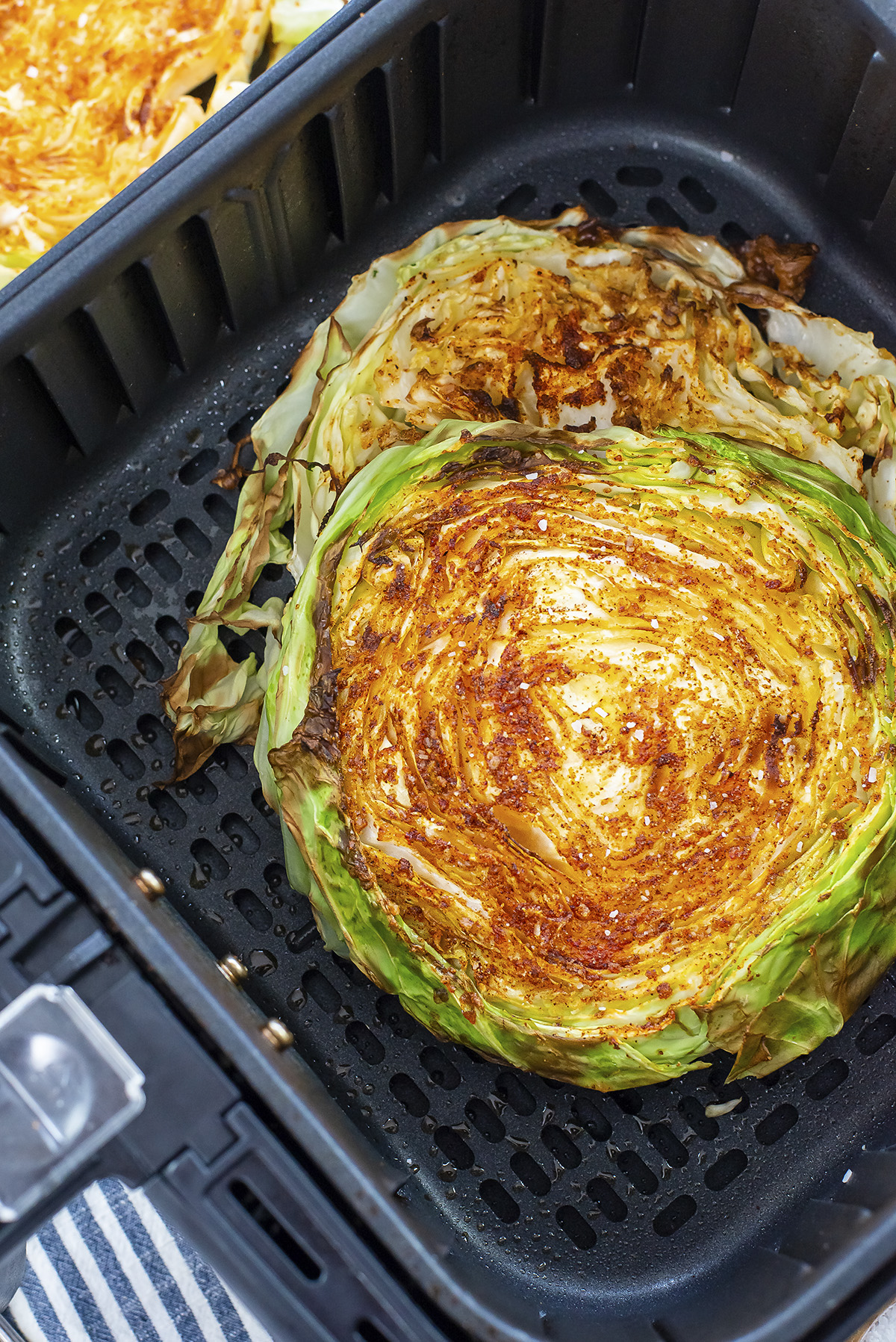 A whole cabbage steak cooked in an air fryer basket.