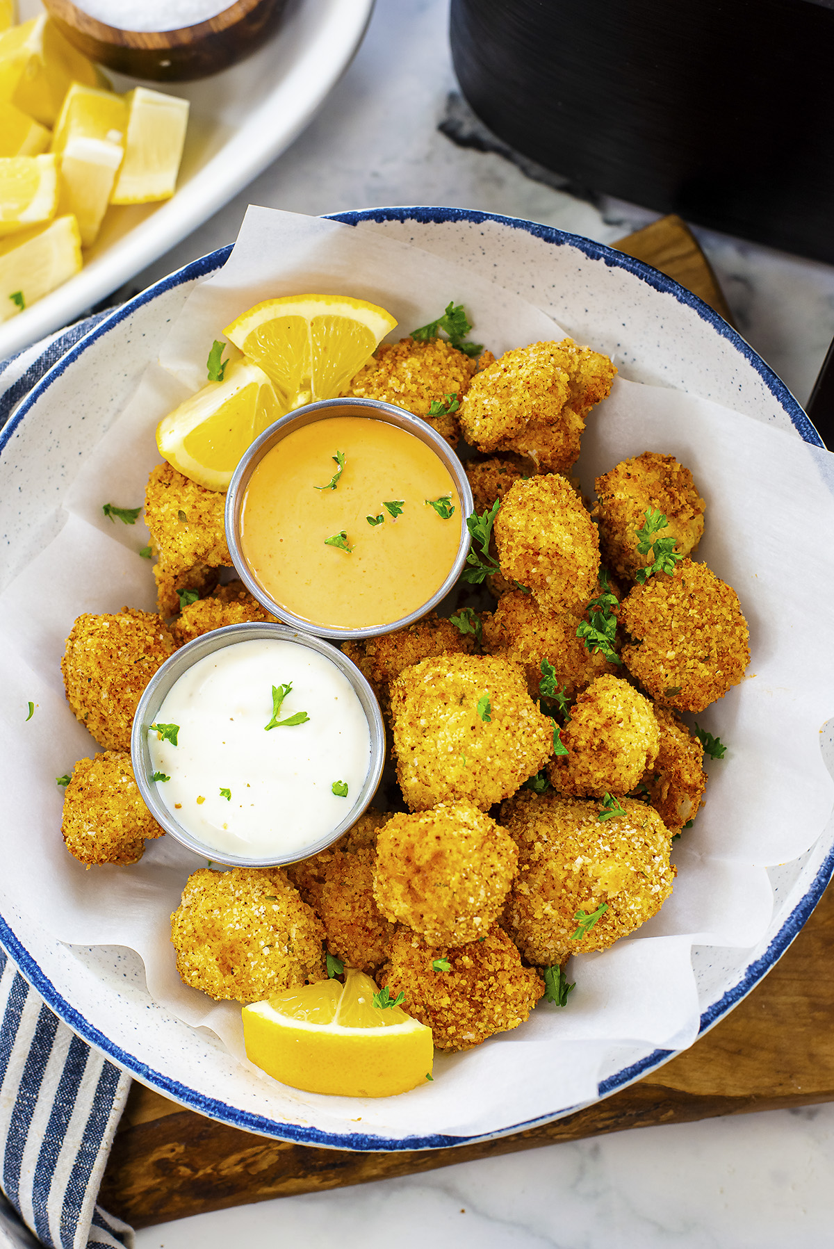 Overhead view of breaded cauliflower in a bowl with two dips.