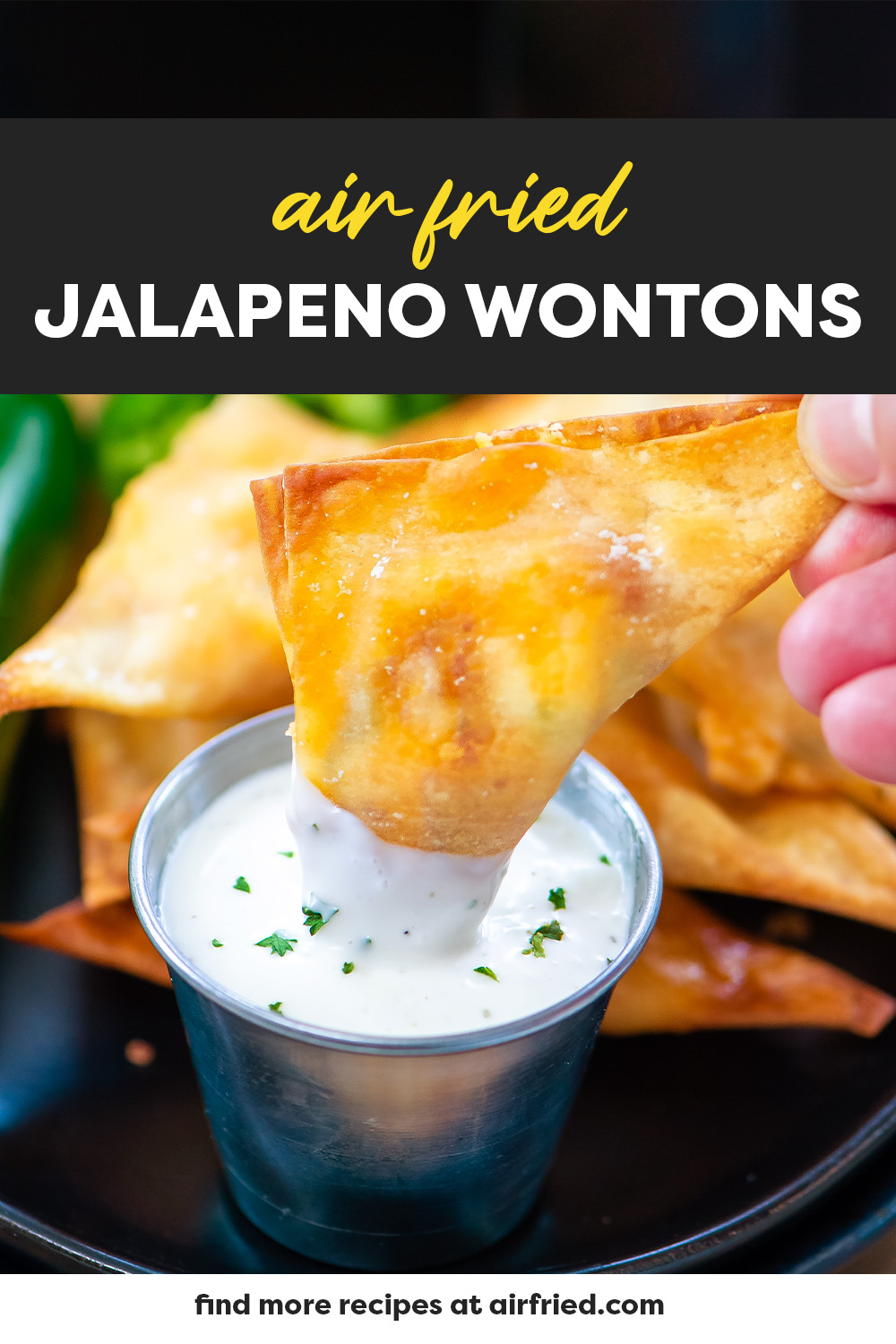 A person dipping a jalapeno wonton into ranch dressing.