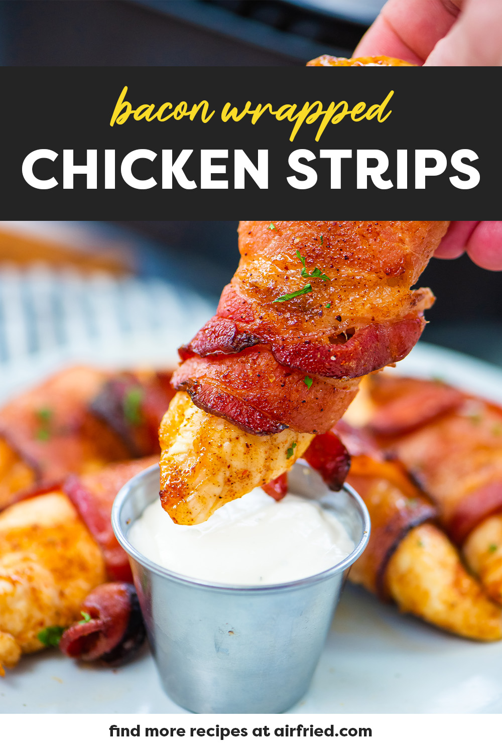 A bacon wrapped chicken strip being dipped into ranch dressing.