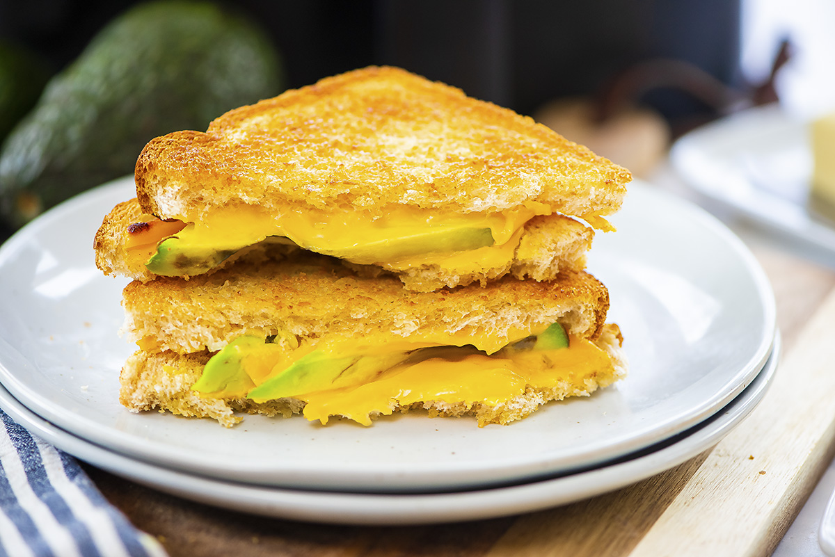 Close up of an avocado grilled cheese cut in half.