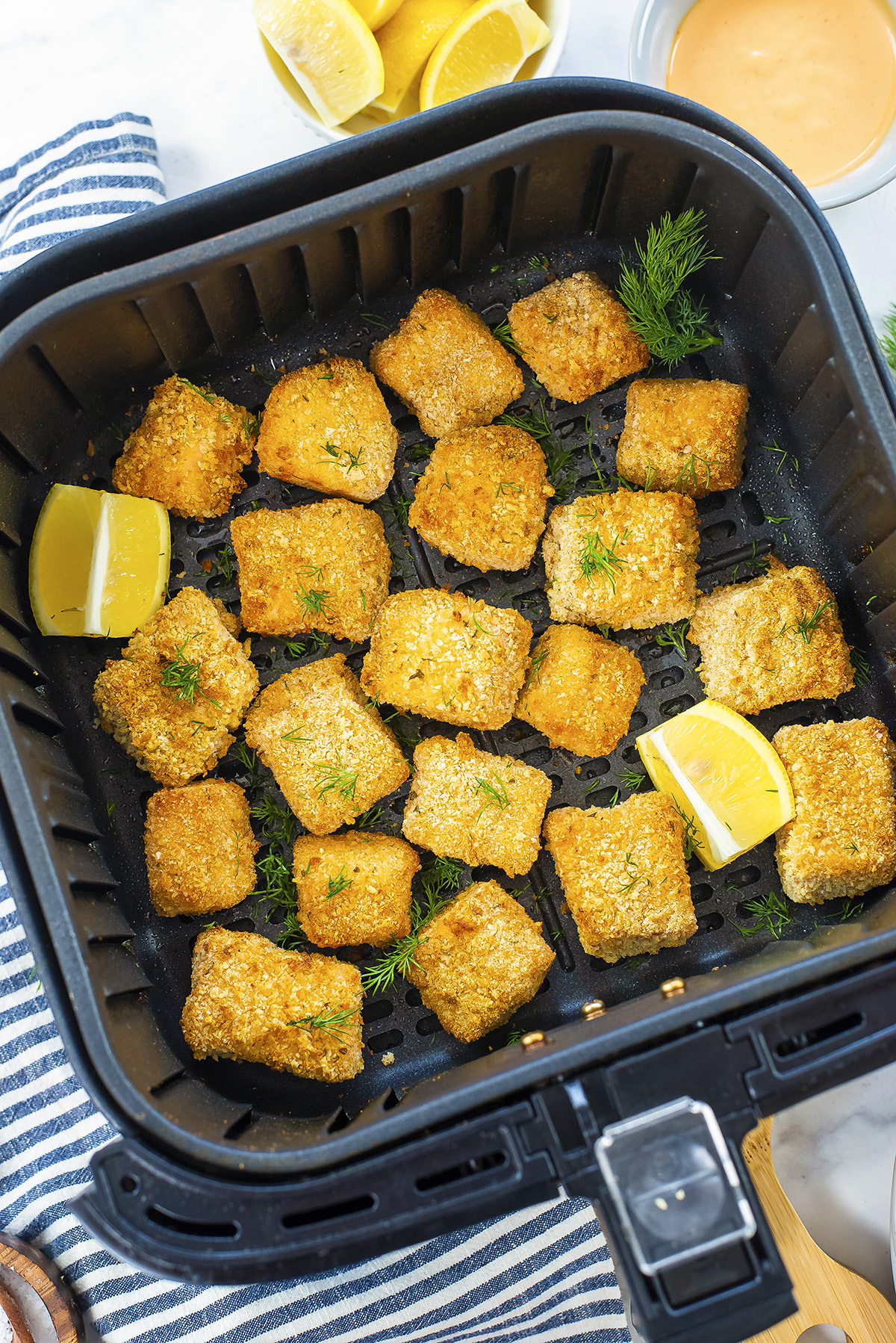 Overhead view of salmon nuggets in an air fryer basket.