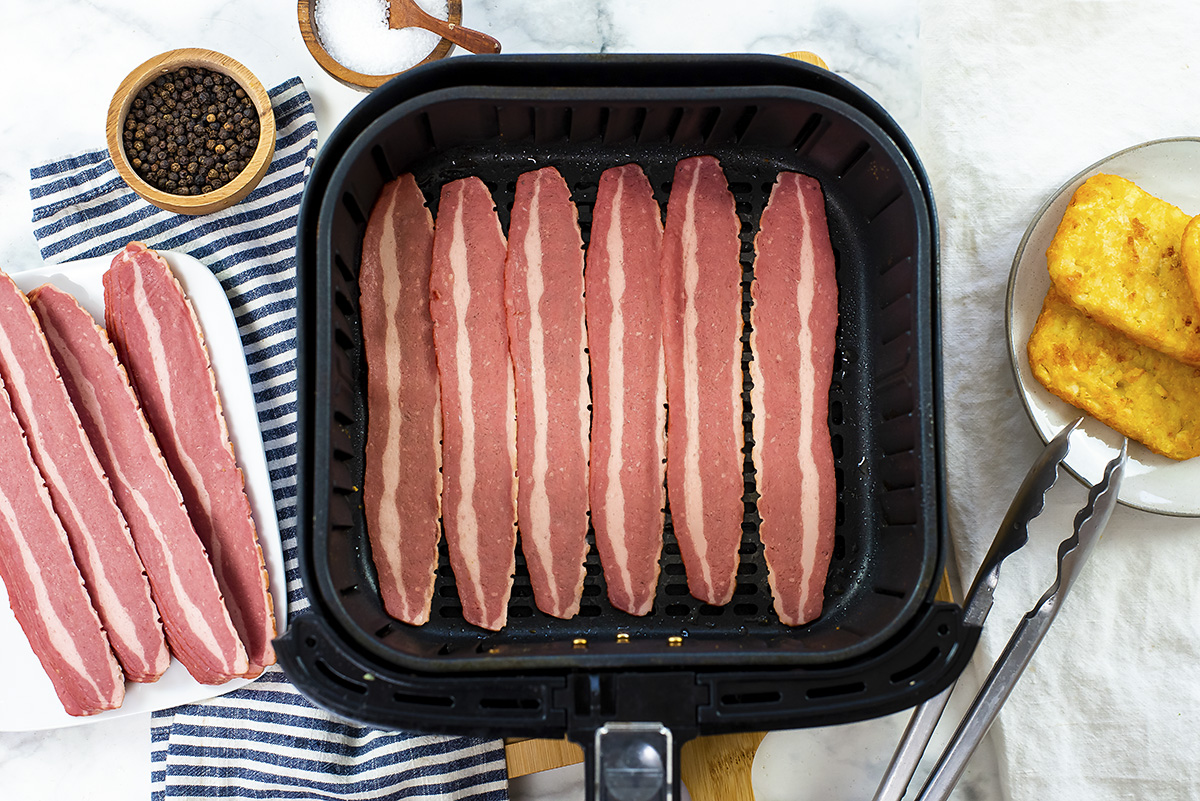 Raw turkey bacon in an air fryer basket.