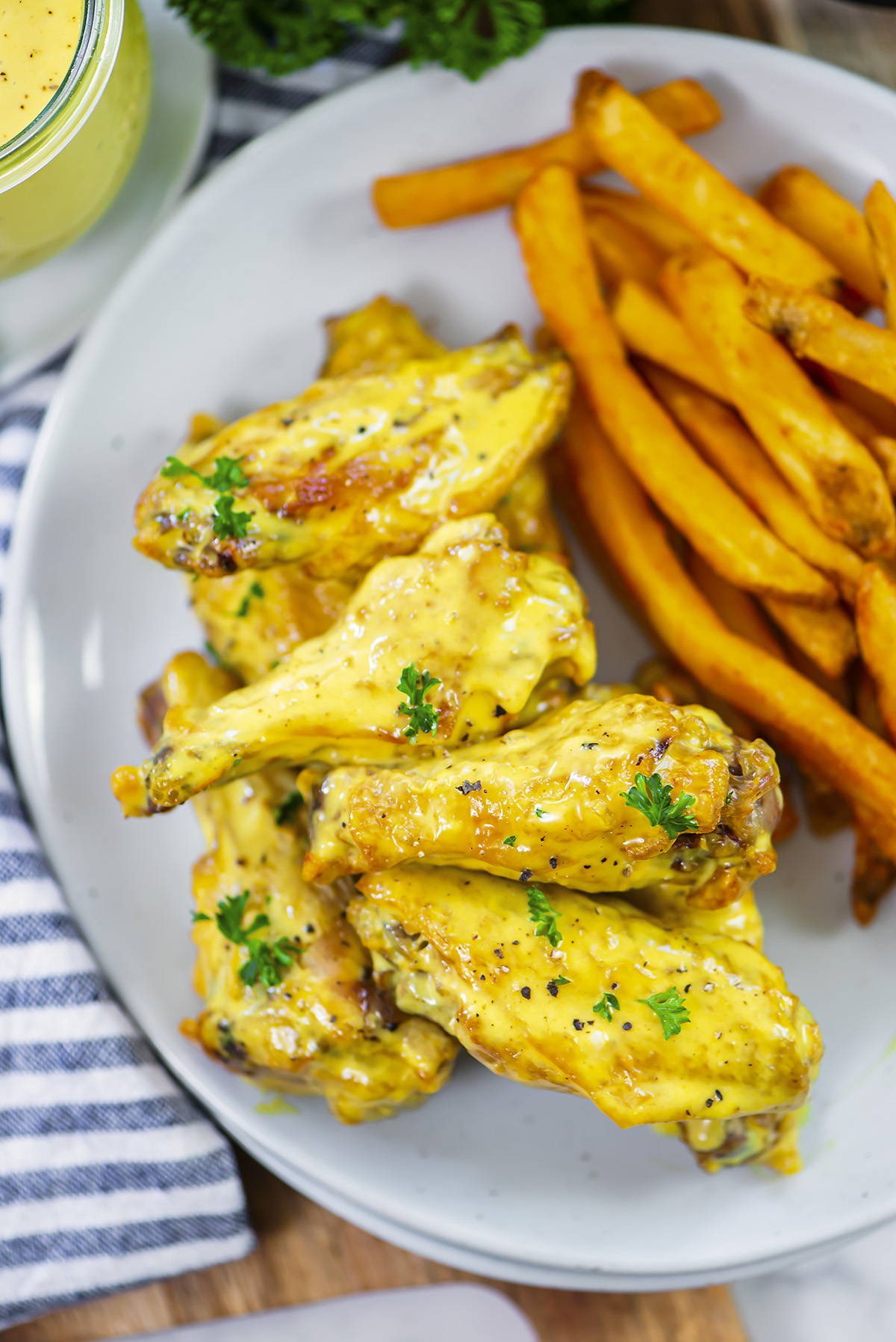 Overhead view of honey mustard wings on a plate with fries.