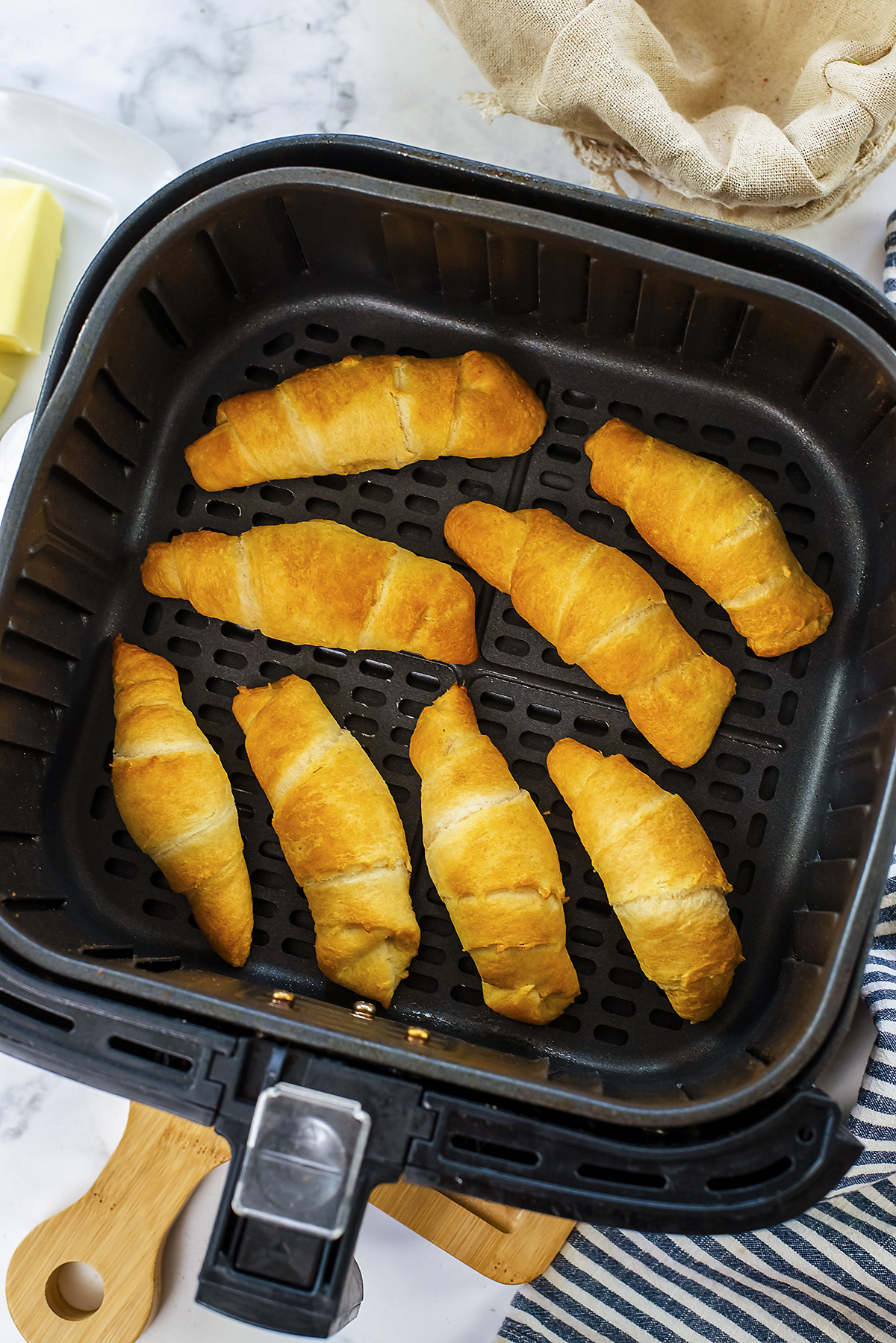Cooked crescent rolls in an air fryer basket.