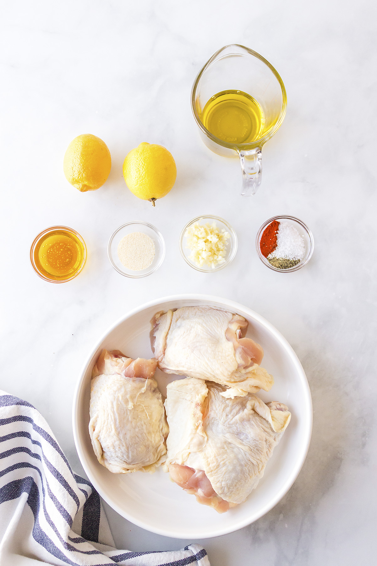 Lemon garlic chicken thigh ingredients on a white countertop.