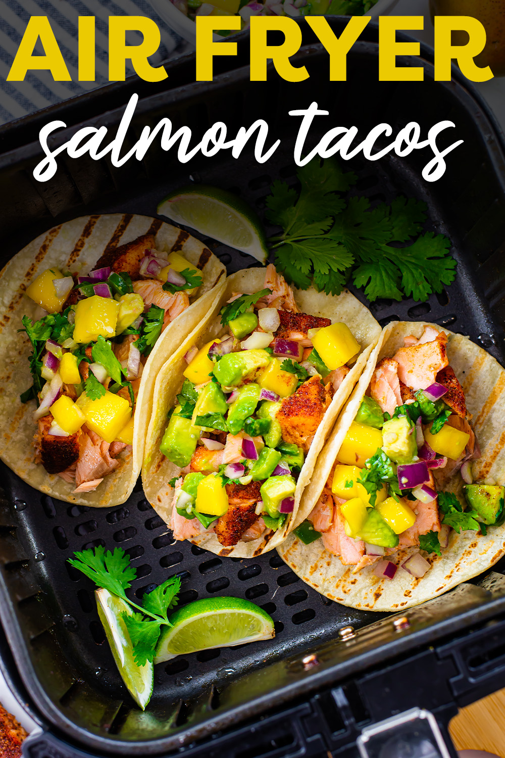Three salmon tacos with mango salsa in an air fryer basket.