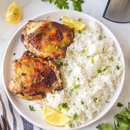 Two chicken thighs on a plate of rice.