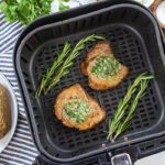 Filet mignon in air fryer basket with herbs.