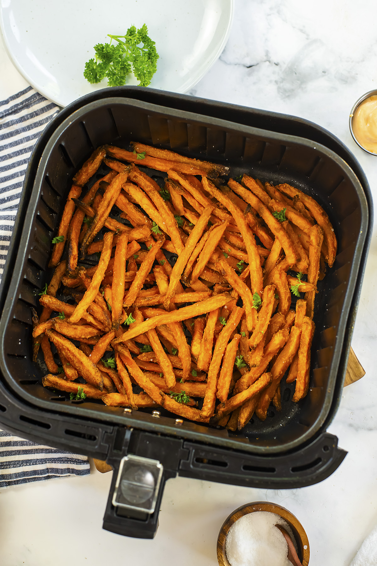 Overhead view of cooked sweet potato fries in an air fryer bsasket.
