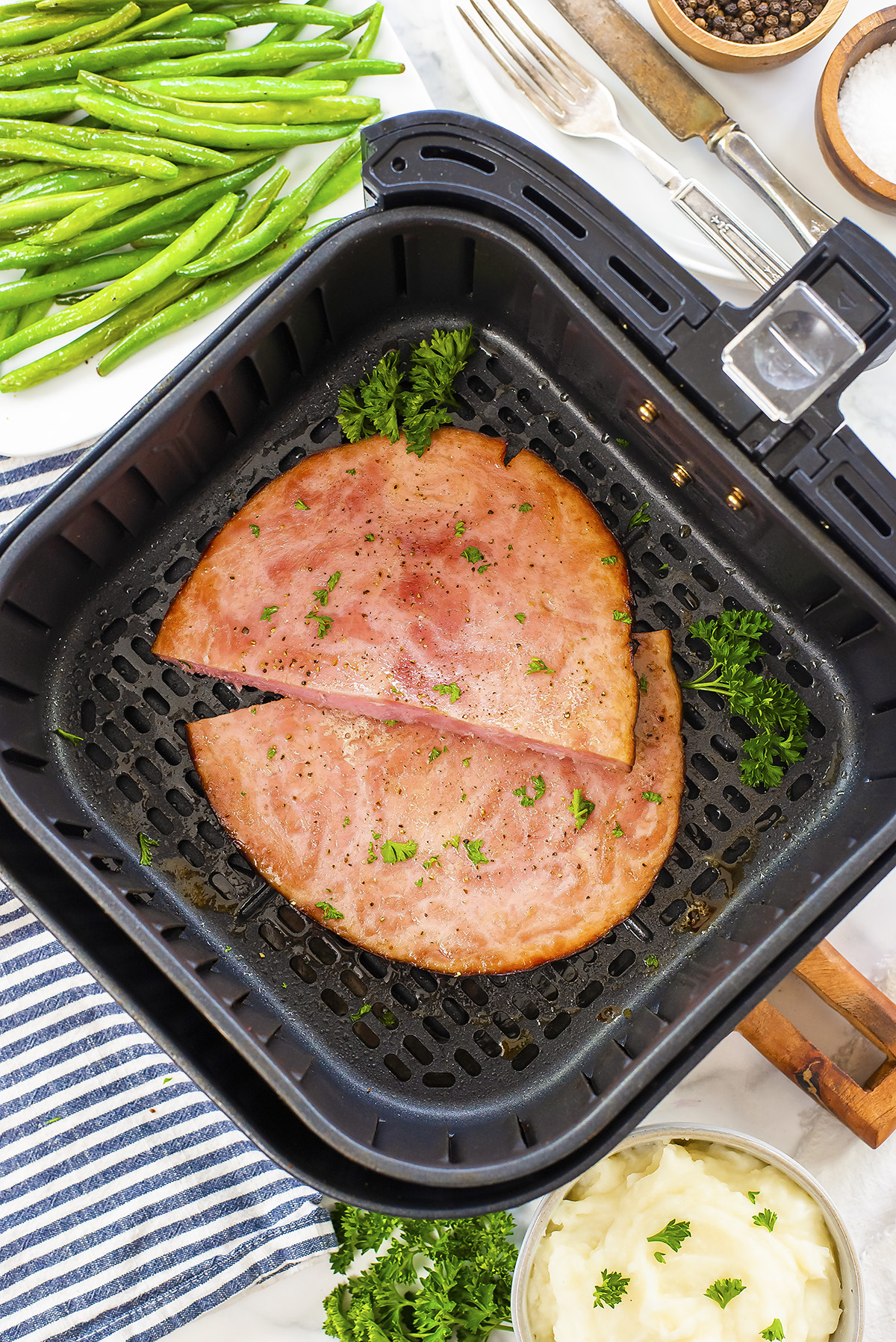 A sliced ham steak in an air fryer basket.