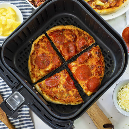 Cooked pizza in an air fryer basket.