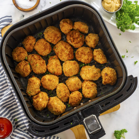 Many tofu nuggets in an air fryer basket.