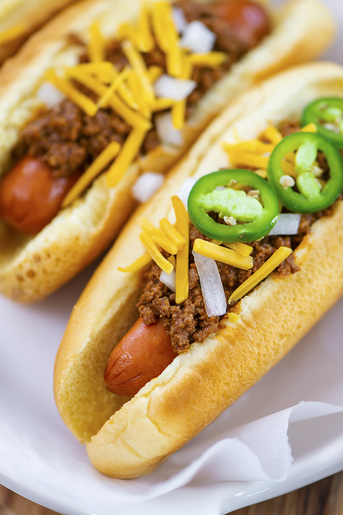 Close up of a chili dog with jalapenos on toop.