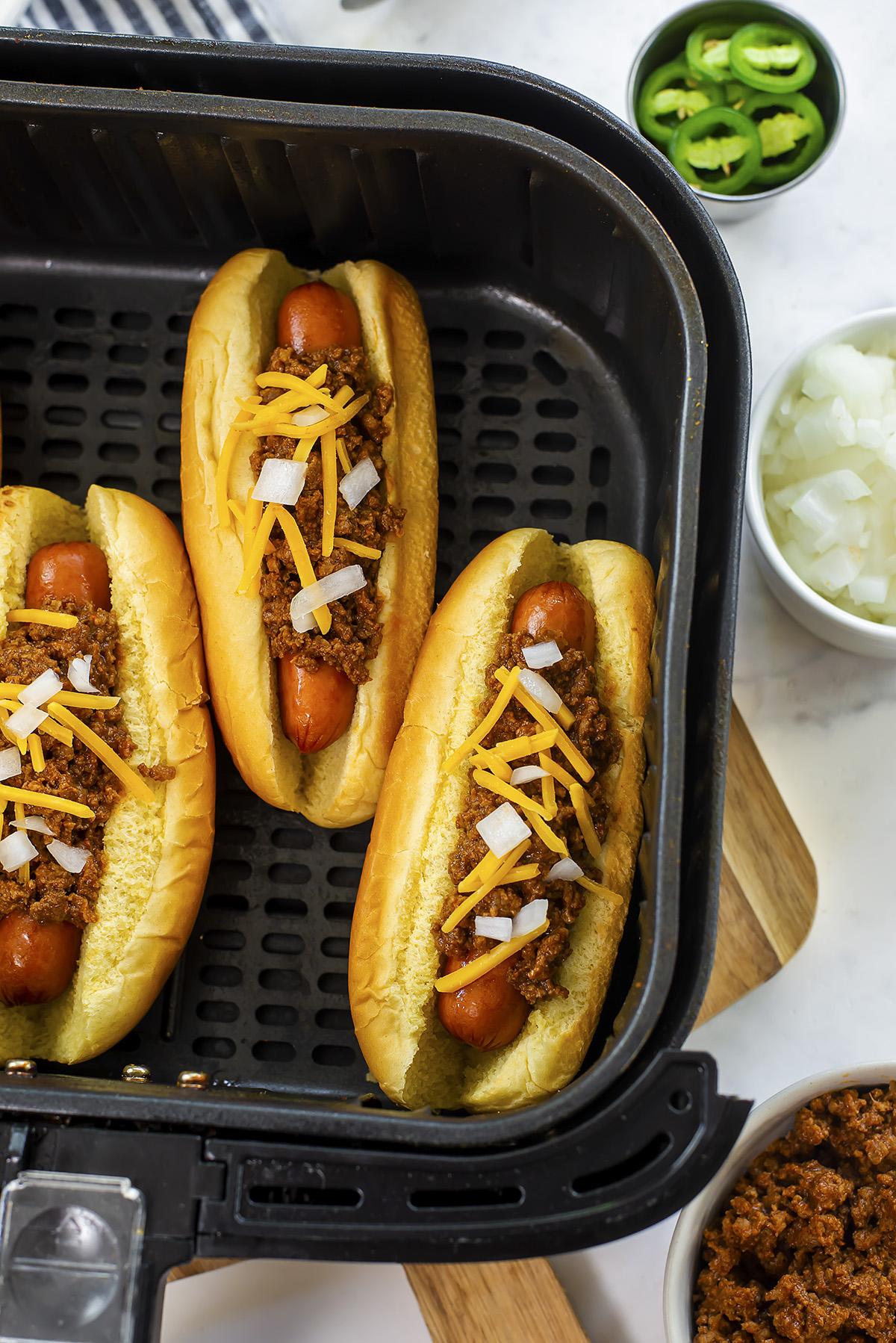 Close up of chili dogs in an air fryer basket.