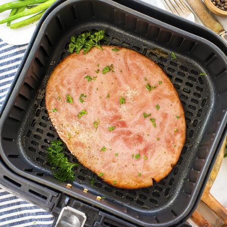A cooked ham steak in an air fryer basket.