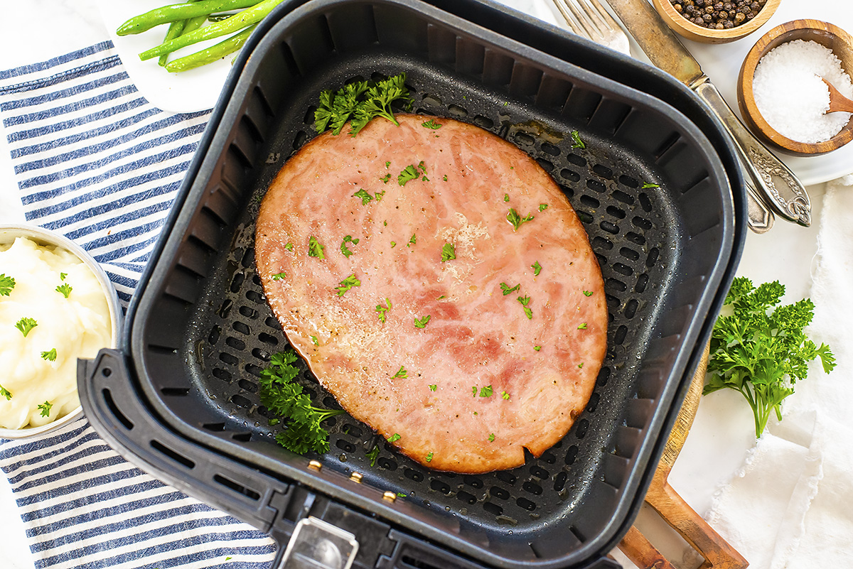 A cooked ham steak in an air fryer basket.
