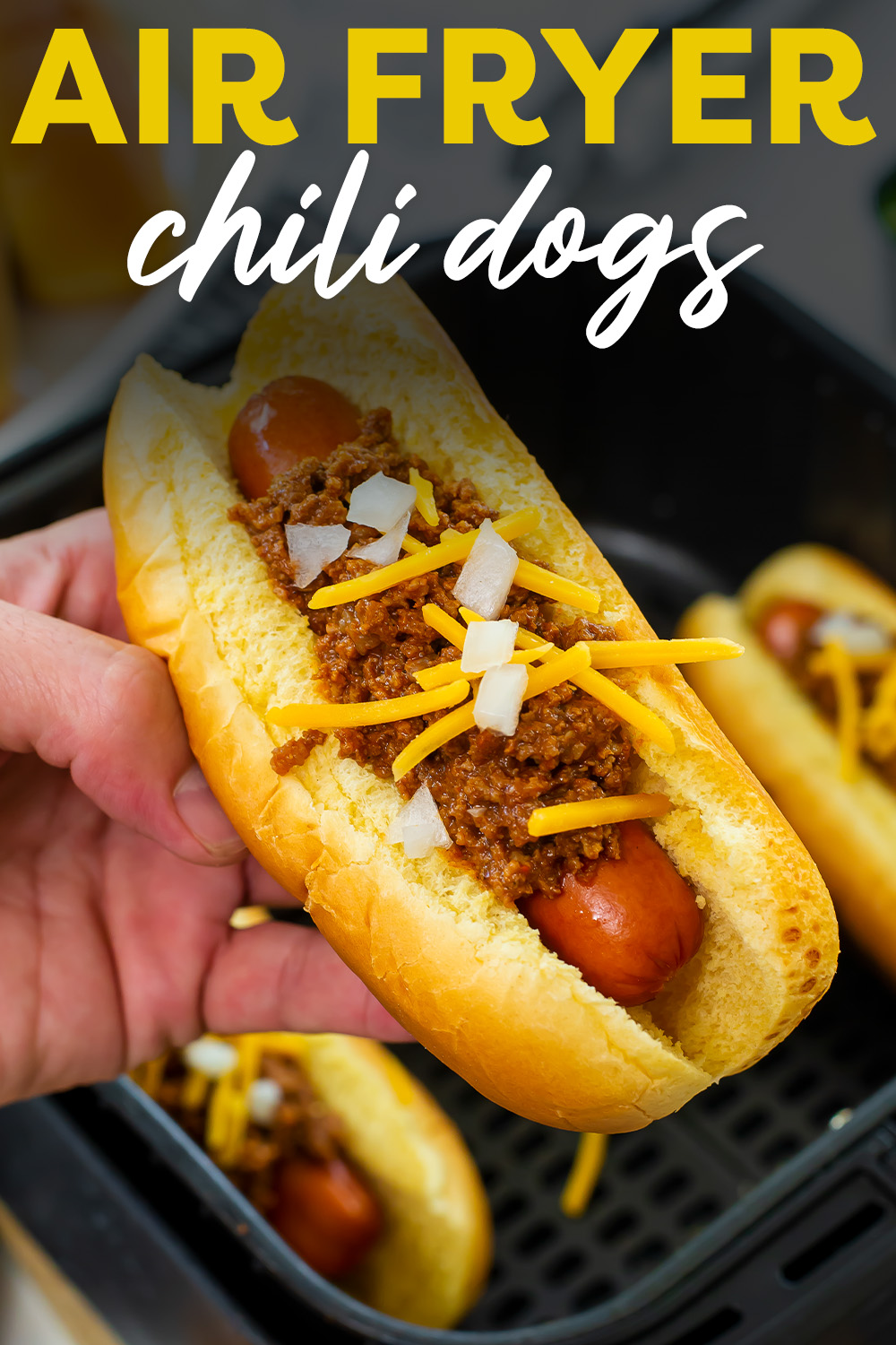 Close up of a person holding a chili dog.
