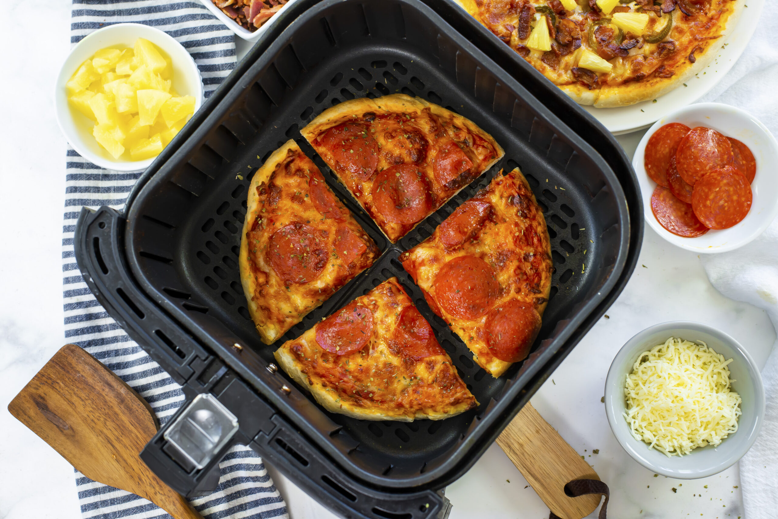 Sliced pizza in an air fryer basket.