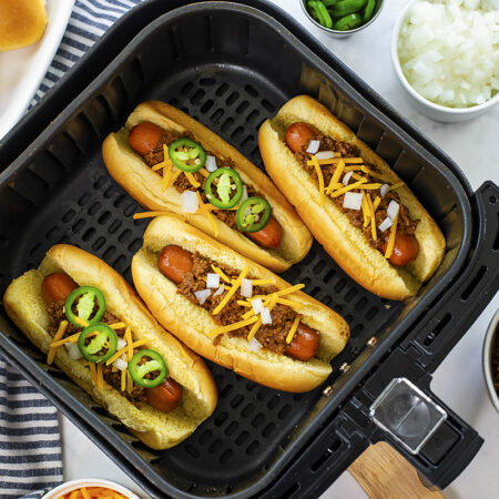 Four chili dogs in an air fryer basket.