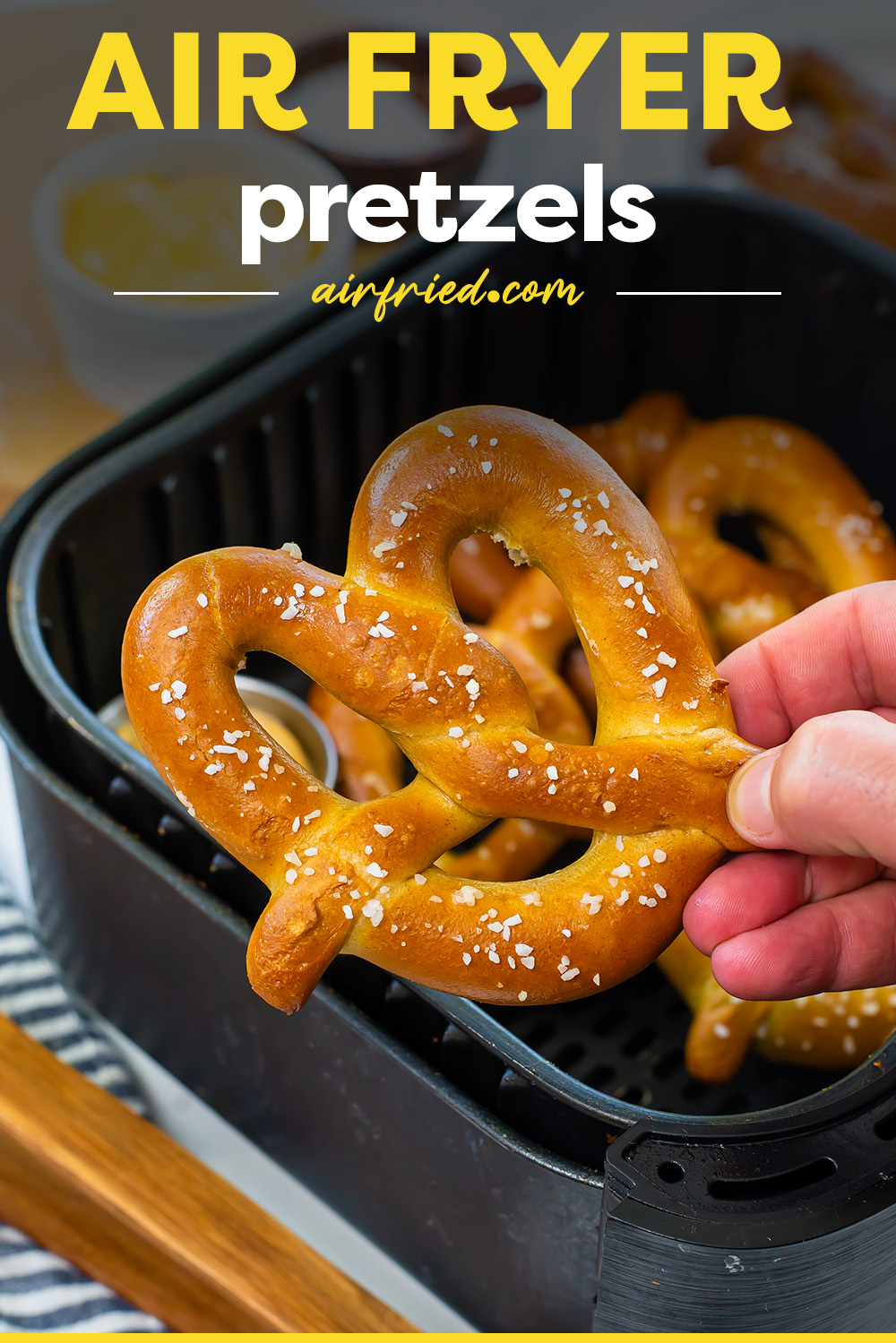 A person holding a cooked pretzel.