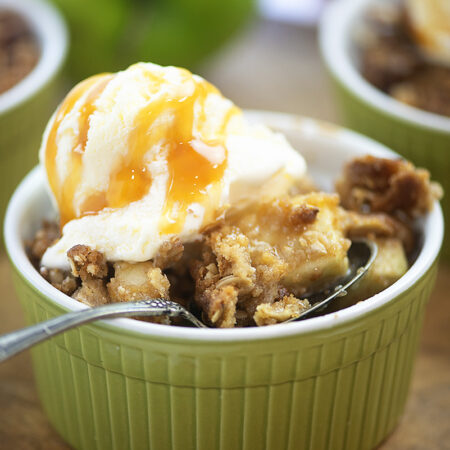 Close up of apple crisp topped with ice cream.