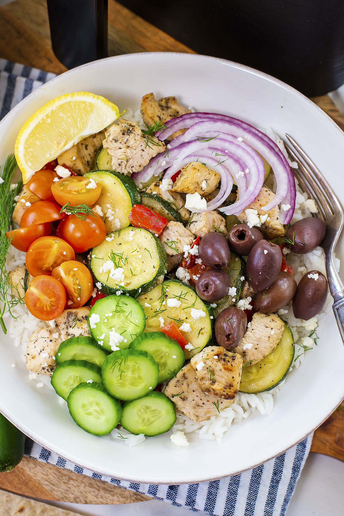 Overhead view of a bowl of Greek chicken topped with tomatoes and onions.