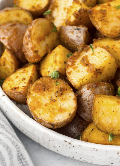 Close up of roasted potatoes in a white bowl.